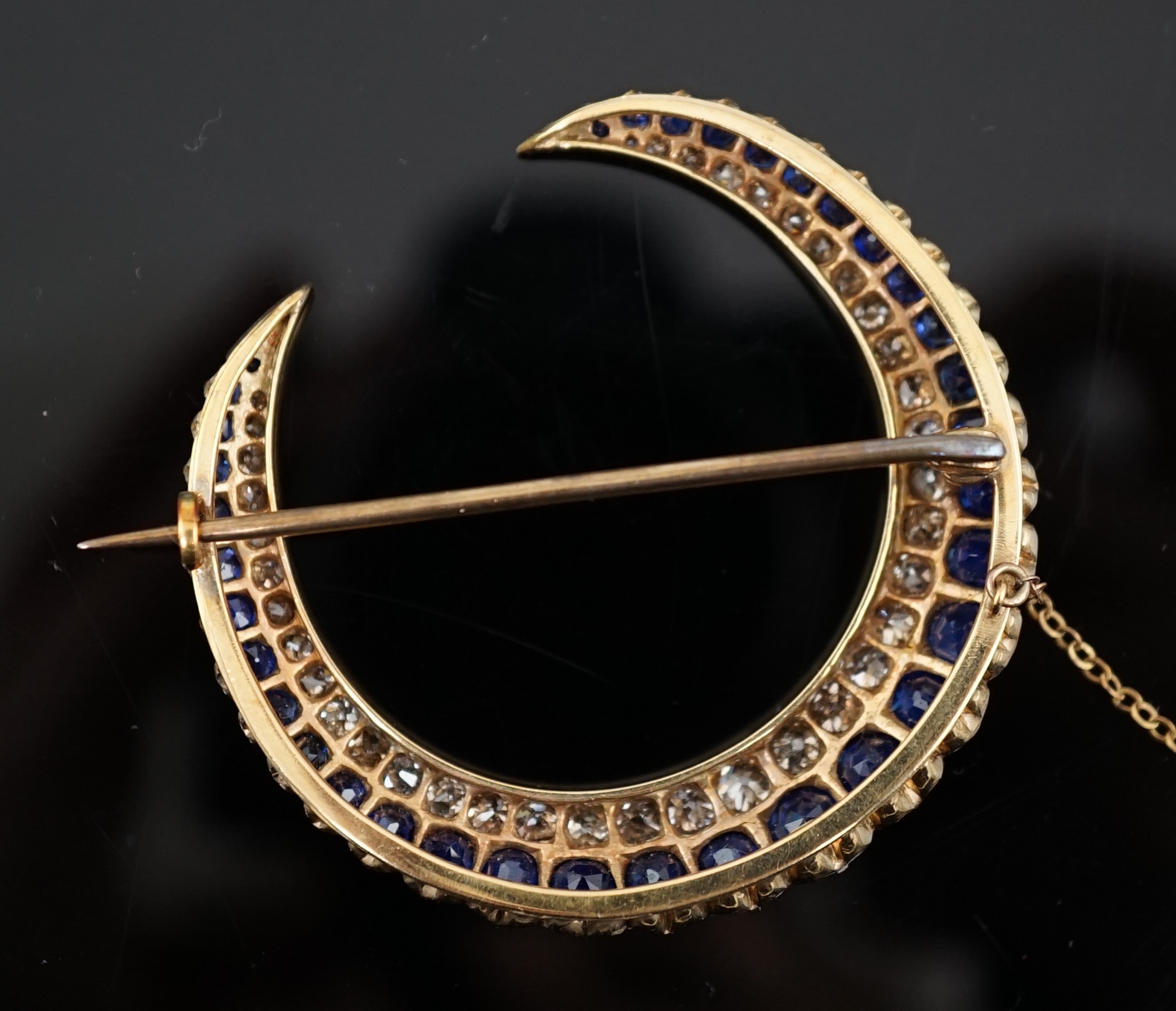 An early to mid 20th century gold, graduated sapphire and graduated diamond set two row crescent brooch